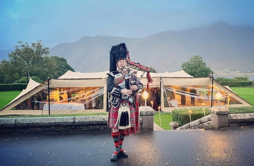Highland Stretch Tent with traditional Scottish bagpiper